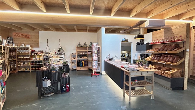 Moderner Laden mit Holzregalen, bestückt mit Produkten; lichtdurchfluteter Raum, keine Personen.